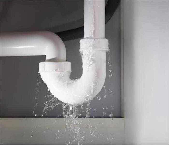 A white pipe is leaking a lot of water.